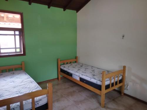 two beds in a room with green walls at Apartamento Duplex a 100 metros da Praia de Boracéia in Bertioga