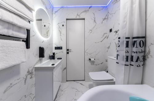 a white bathroom with a toilet and a sink at MYFREEDOM Апартаменти пр-т Правди 6 in Kyiv