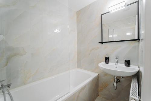 y baño con lavabo, bañera y espejo. en Double Floor Apartment With 2 Terraces en Veľká Lomnica