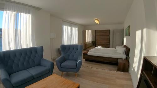 a living room with a blue chair and a bed at Henry's Apartments Interlaken in Interlaken