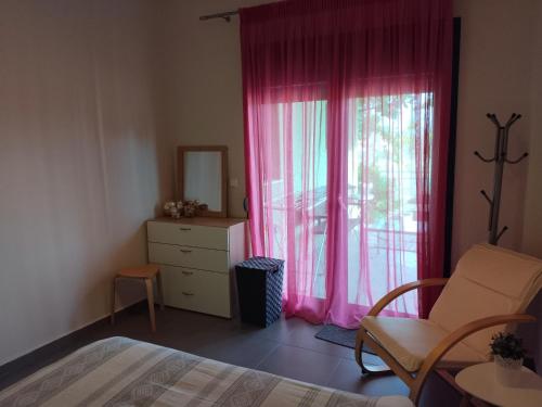 green guesthouse في كوموتيني: غرفة نوم مع سرير ونافذة مع ستائر وردية