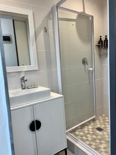 uma casa de banho branca com um lavatório e um chuveiro em G’s Self Catering Apartments na Cidade do Cabo