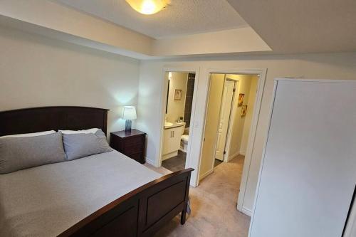 a bedroom with a large bed and a bathroom at Modern 2BR Townhouse w Patio & Free Parking Family & Work Stays in Toronto