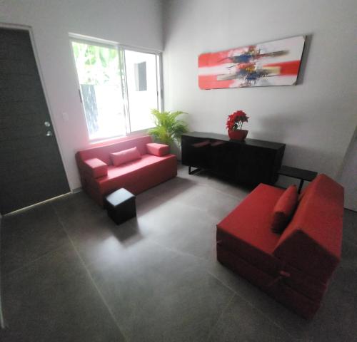 a living room with red furniture and a red couch at CASA MARIPOSA en Punta Leona a 500 metros de la playa FULL EQUIPADA Espacio y precio a tu medida Posibilidad de alquilar la casa entera, los dos apartamentos abajo o los 2 cuartos con baños privados en la planta alta Para 1 a 22 personas in Herradura