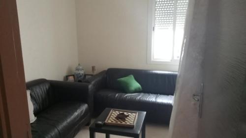 a living room with a black leather couch and a table at Appartement a skhirat in Skhirat
