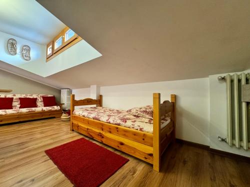 a bedroom with two beds and a red rug at Liuby Home in Sestriere