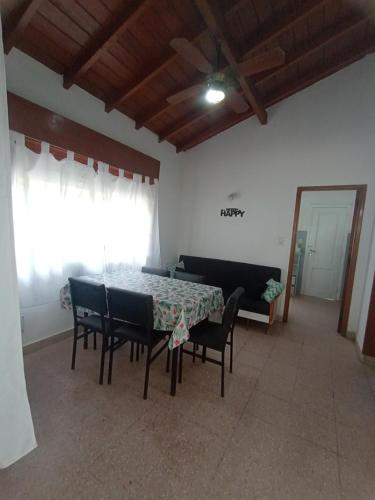 a dining room with a table and chairs and a couch at Casasodali in Villa Gesell