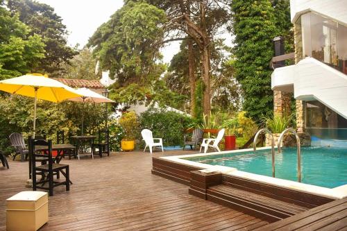 una piscina con mesa, sillas y sombrilla en Piedras Doradas Hotel y Spa en Valeria del Mar