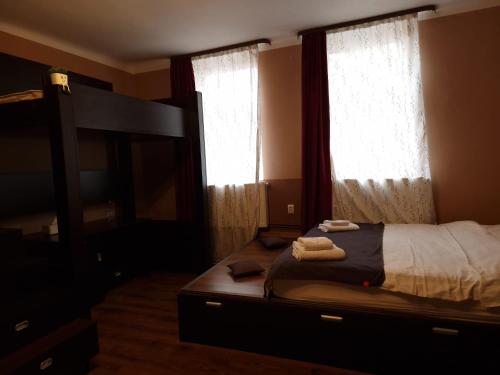 1 dormitorio con 1 cama y 2 ventanas con cortinas en M&A Mario Ultra Central Apartament, en Brasov