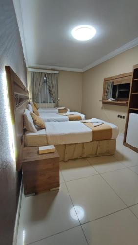 Una habitación con dos camas y una mesa dentro. en Razana Al-Hafaer, en La Meca