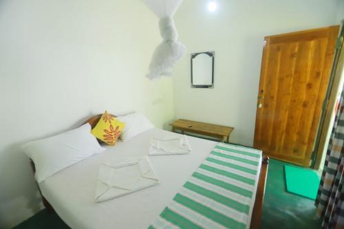 1 dormitorio con 1 cama blanca y 2 almohadas en Sigiri Green Shadow Homestay en Sigiriya