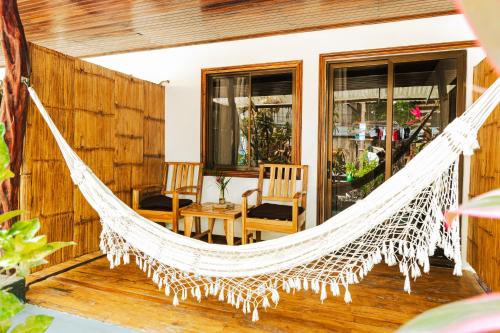 a hammock on the porch of a house at El Gato Rojas Surf Hostel in Santa Teresa Beach