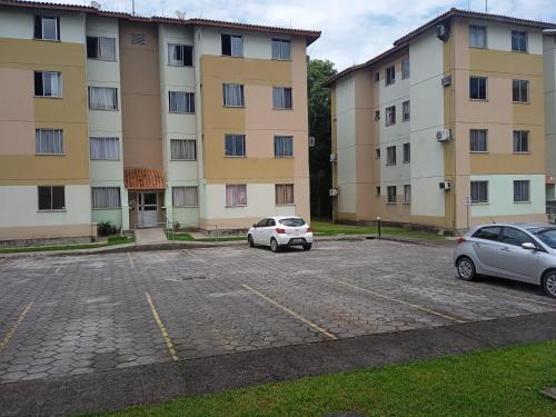 two cars parked in a parking lot in front of a building at Apto 2px.unesc in Criciúma