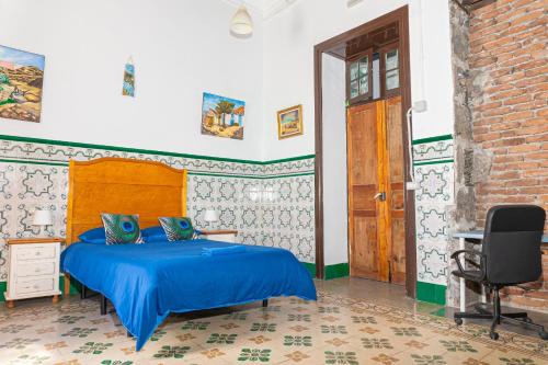 1 dormitorio con cama azul y puerta de madera en Atlantis Surf Hostel, en Moya