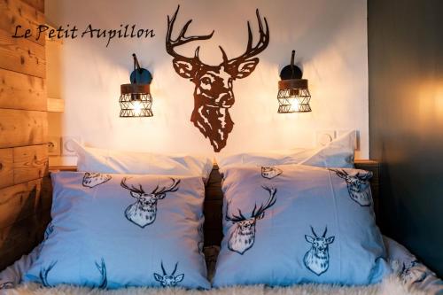Una cama con almohadas con cabezas de ciervo. en Le Petit Aupillon - L'Aupillon des Forêts - 2 studios cocooning aux Orres, en Les Orres