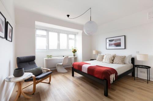 a white bedroom with a bed and a chair at SPACIOUS Apartment in London