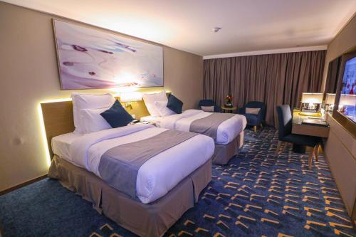ウナイザにあるفندق شيرفل الواحة عنيزة Cheerful Al Waha Unayzah Hotelのベッド2台とテレビが備わるホテルルームです。