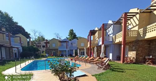 a swimming pool in a yard next to some apartments at Ydna Apartments in Possidi