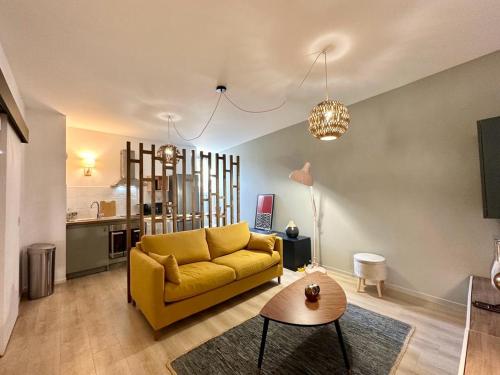 un salon avec un canapé jaune et une table dans l'établissement LE PANCAUT- Chaleureux - Hyper Centre, à Mont-de-Marsan
