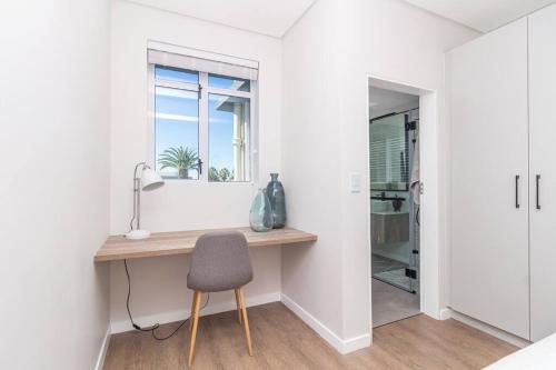 een kamer met een bureau met een stoel en een raam bij Contemporary central apt. Between beach and city. in Kaapstad