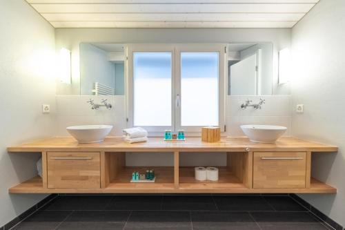 une salle de bain avec deux lavabos et un grand miroir dans l'établissement The Glacier Express Apartment - GRINDELHOMES, à Grindelwald