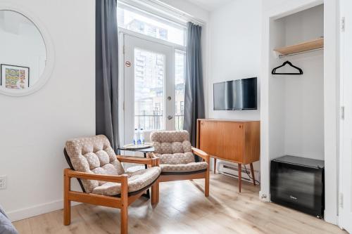a living room with two chairs and a television at hotel le coach in Montréal
