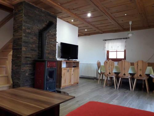 een woonkamer met een open haard en een tafel en stoelen bij Chalet Brložnica pod Veliko planino in Luče