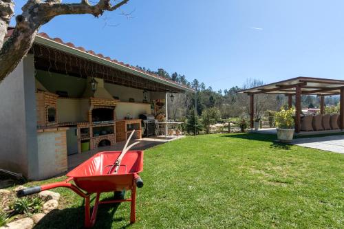 a red wheelbarrow sitting in a yard next to a house at Quinta do Rio Alva and Glamping Lodges in Mouronho