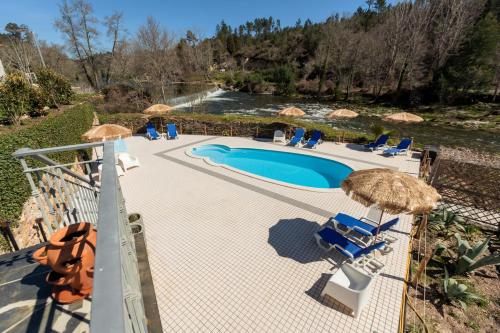 Blick auf einen Pool mit Sonnenschirmen und Stühlen in der Unterkunft Quinta do Rio Alva and Glamping Lodges in Mouronho