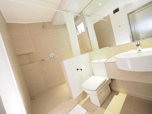 a bathroom with a sink and a toilet and a mirror at Le Beachclub in Pereybere