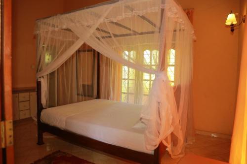 a bedroom with a canopy bed with a window at Amelia 31 in Tangalle