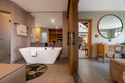 a bathroom with a large tub and a living room at Bakubung Villas in Pilanesberg