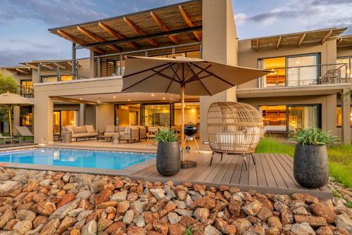 a house with a swimming pool and an umbrella at Bakubung Villas in Pilanesberg