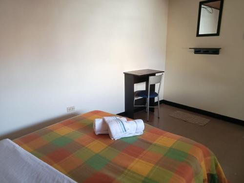 Un dormitorio con una cama con una manta de colores y un escritorio. en Casa Tundama, en Duitama