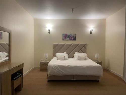 a bedroom with a large bed with two lamps and a television at Seer Furnished Apartments صير للشقق المفروشة in Abu Dhabi