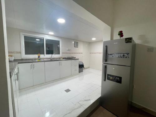 duża kuchnia z lodówką i oknem w obiekcie Seer Furnished Apartments صير للشقق المفروشة w Abu Zabi