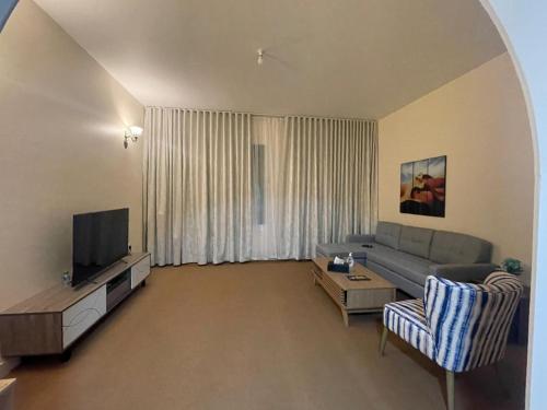 a living room with a couch and a tv at Seer Furnished Apartments صير للشقق المفروشة in Abu Dhabi
