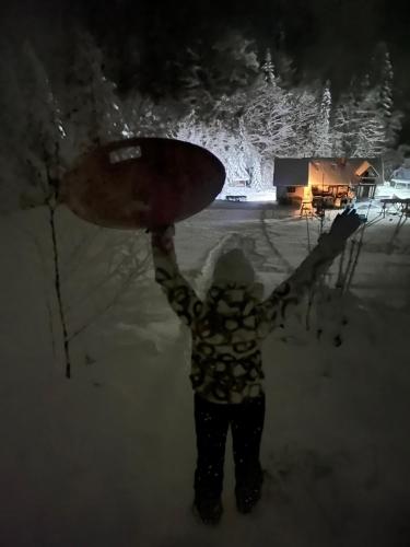 a person holding a snowboard in the snow at night at Apartamenty Kadłubek in Wisła