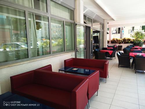un ristorante con sedie rosse, tavoli e tavoli di Hotel Firenze a Bibione