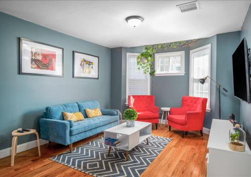 a living room with a blue couch and two red chairs at Colorful, Comfy & Modern - Close to NYC - Parking! in Mount Vernon