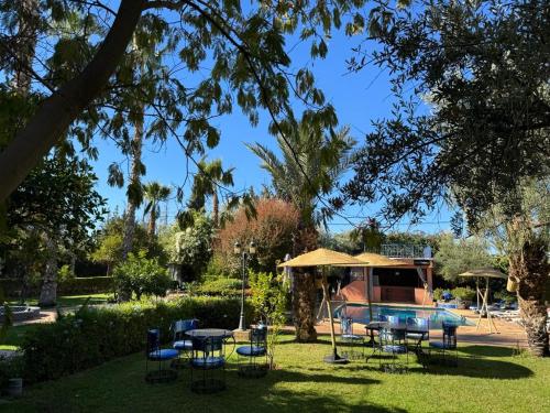 a park with tables and chairs and an umbrella at RIAD REDWAN in Marrakech