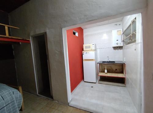 una pequeña cocina con nevera blanca y pared roja en Departamento Planta Baja. Centro. Pileta en Formosa