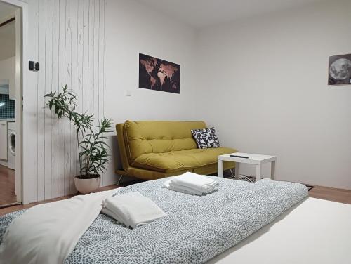 ein Wohnzimmer mit einem Bett und einem gelben Sofa in der Unterkunft Apartmán Brno-Bystrc in Brünn