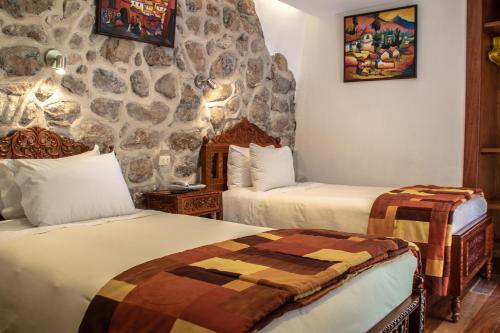 a room with two beds and a stone wall at Amaru Inca in Cusco