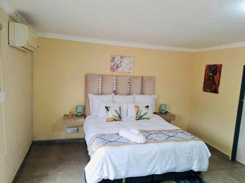 a bedroom with a large white bed with two pillows at The Rose @ C-rane Lodge in Phalaborwa