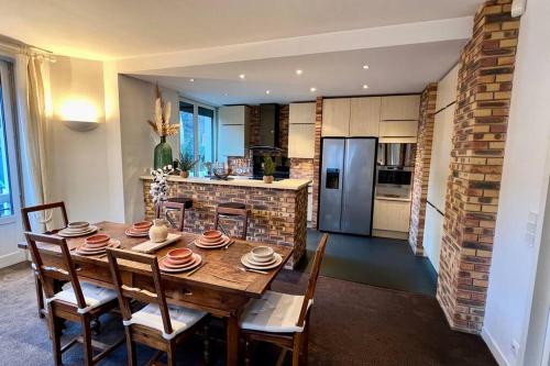 une cuisine avec une table en bois avec des chaises et un réfrigérateur dans l'établissement Le loft d'Étigny, à Luchon
