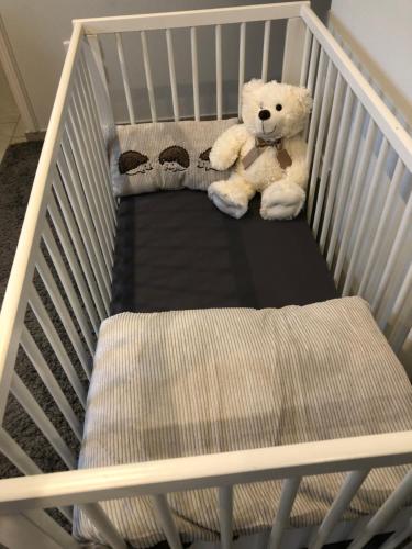 ein Teddybär auf einem Kinderbett in der Unterkunft Appartement -Villa ROYAL in Oberlauterbach