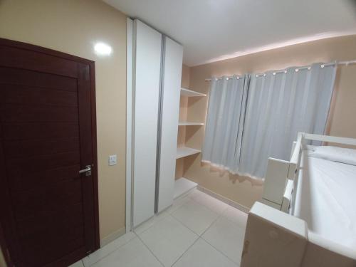 a bathroom with a toilet and a door and shelves at Golden Apartament's Porto de Galinhas in Porto De Galinhas