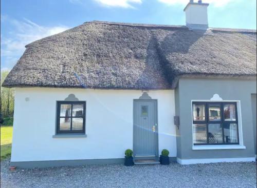 een klein wit huis met een rieten dak bij The Robins Rest in Killarney