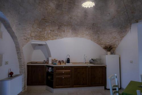 a kitchen with a refrigerator and a stone wall at I trulli di Nonno Battista in Locorotondo
